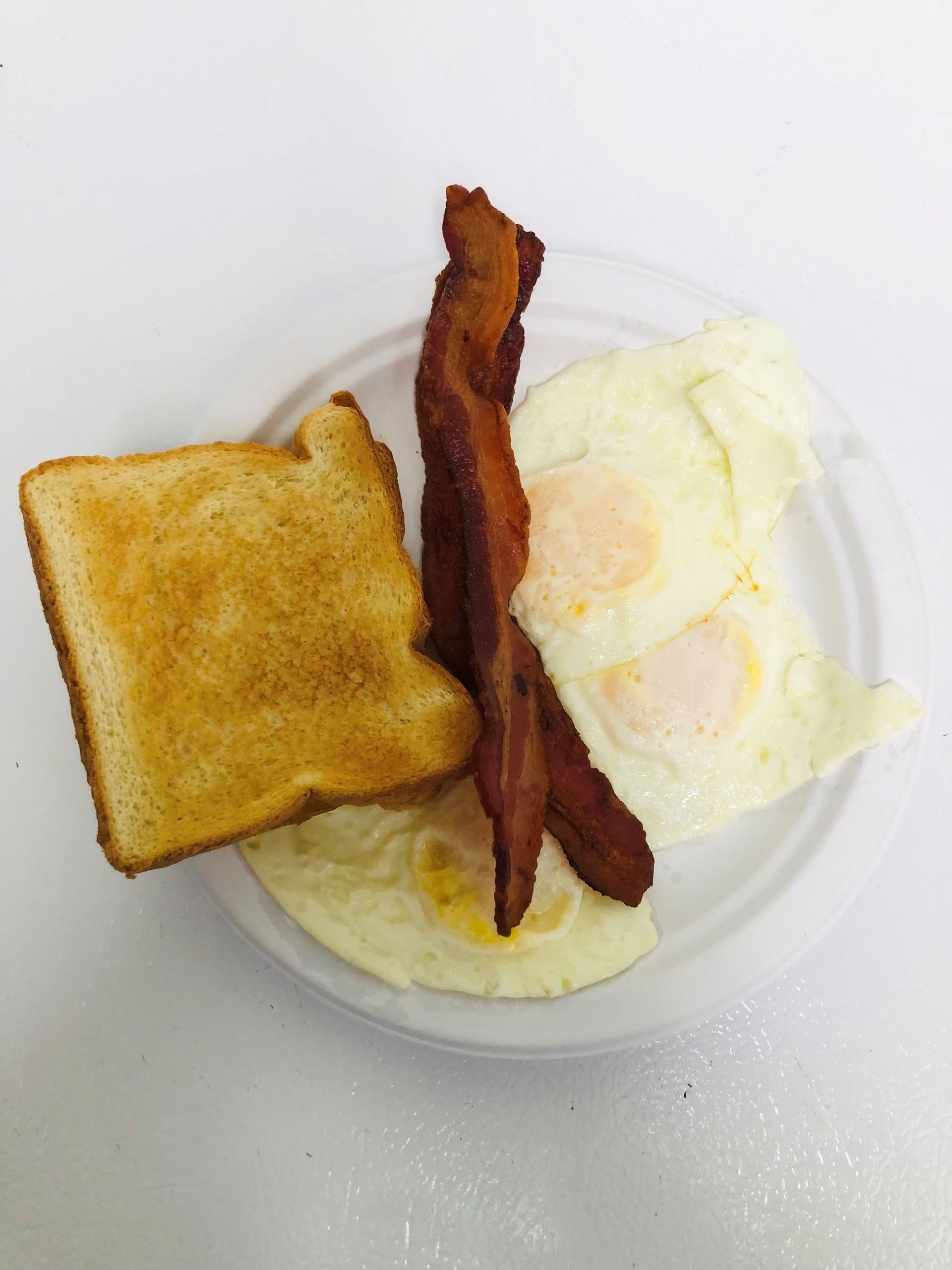 A white plate topped with eggs bacon and toast