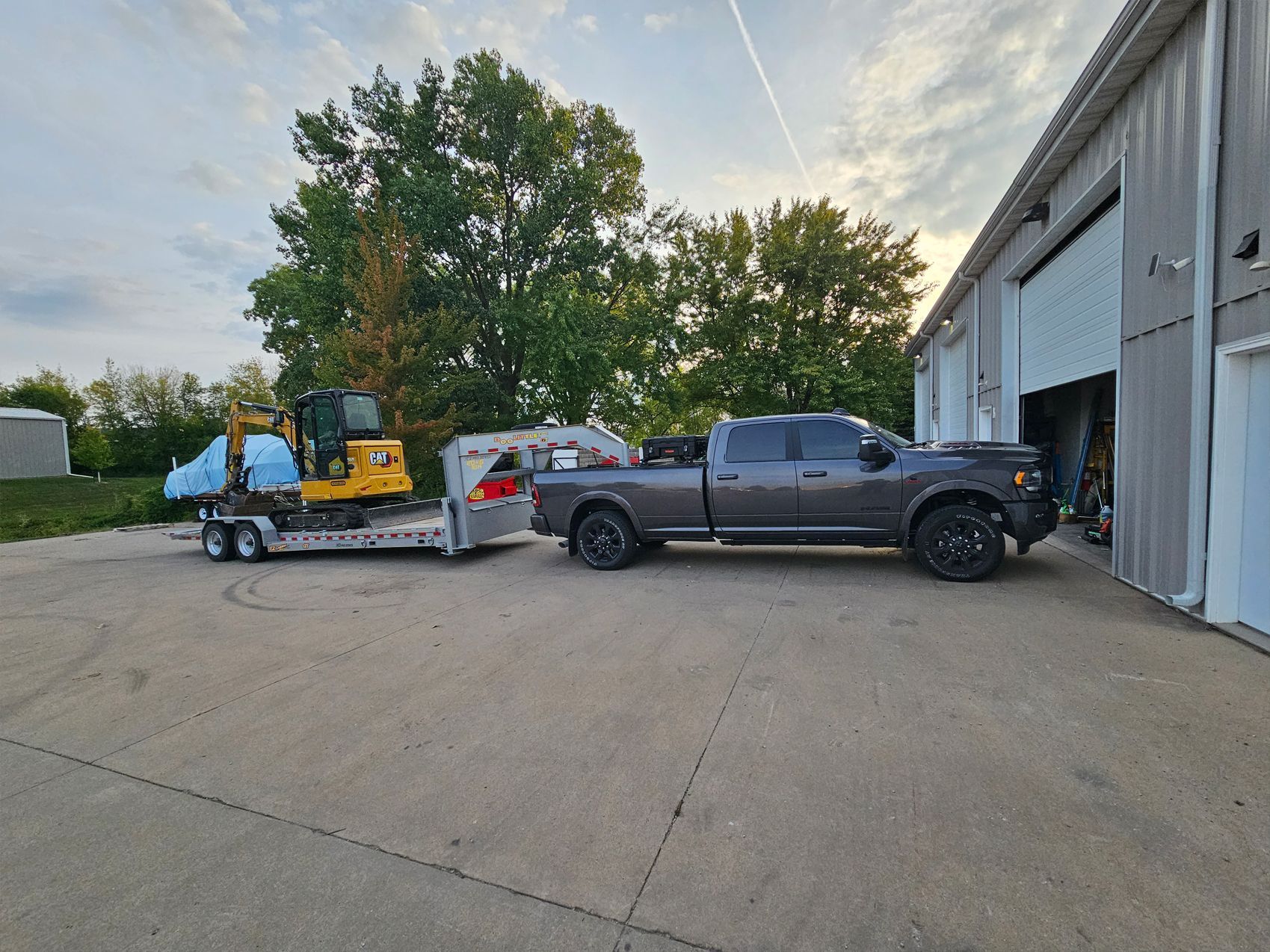 A truck is towing a trailer with an excavator on it.