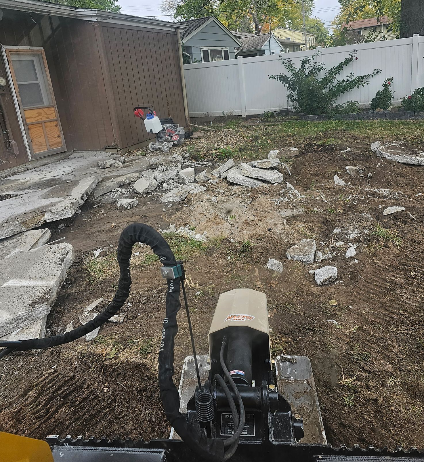 A stump grinder is being used to remove a tree stump in a backyard.