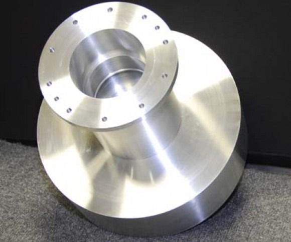 Shiny metal industrial flange with bolt holes on a dark surface