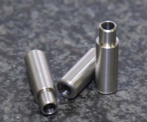 Three silver metal cylindrical parts on a gray surface, one standing upright and two lying down