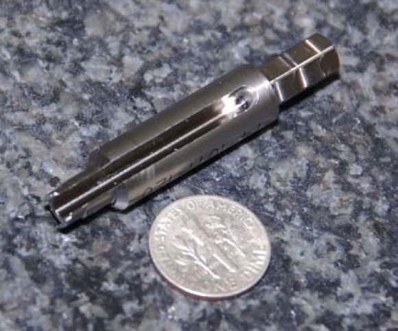 Metal pen-like tool beside a coin on a speckled countertop
