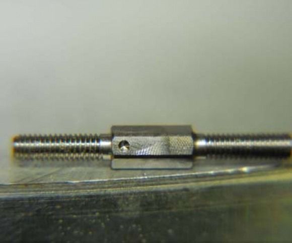 Metal threaded rod with a central hex coupler on a reflective surface