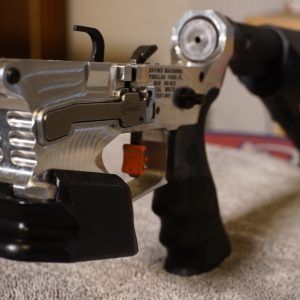 Close-up of a silver and black stapler on a tabletop, with a blurred hand in the background