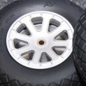Close-up of a silver wheel hub with a central hole beside a black tire tread.