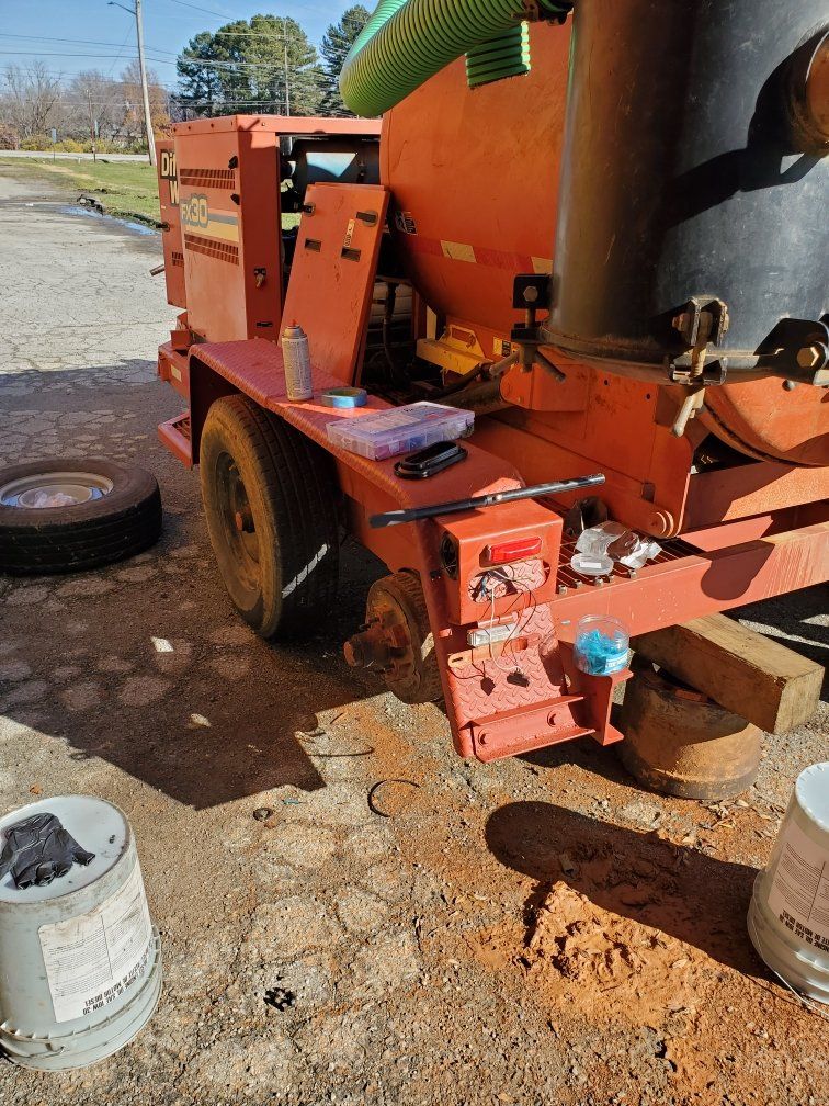 A red vacuum truck is parked on the side of the road.