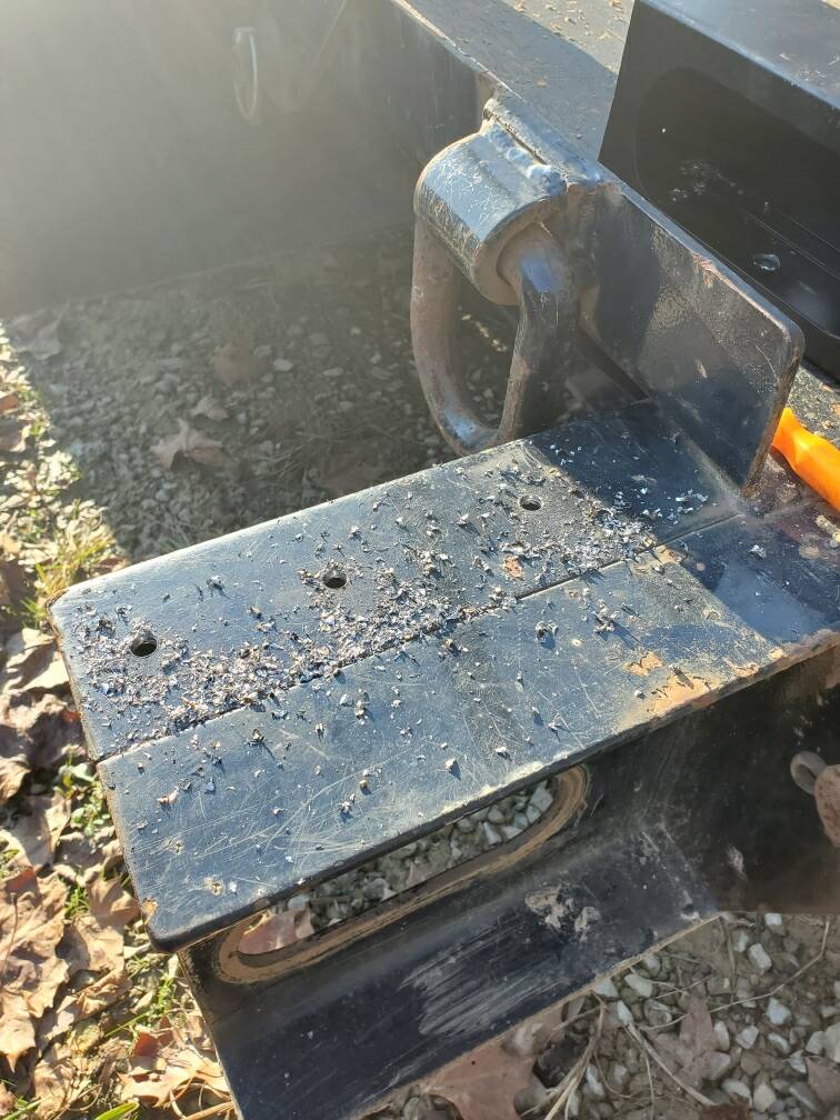 A piece of metal is sitting on the ground next to a car.
