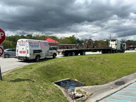 A white van is parked in a parking lot next to a truck.