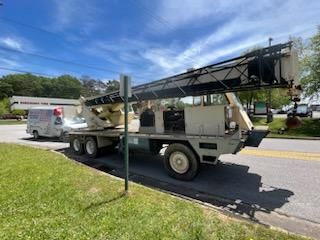 A large crane is parked on the side of the road next to a white van.