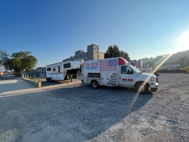 A white van with an American flag on the side is parked next to a trailer