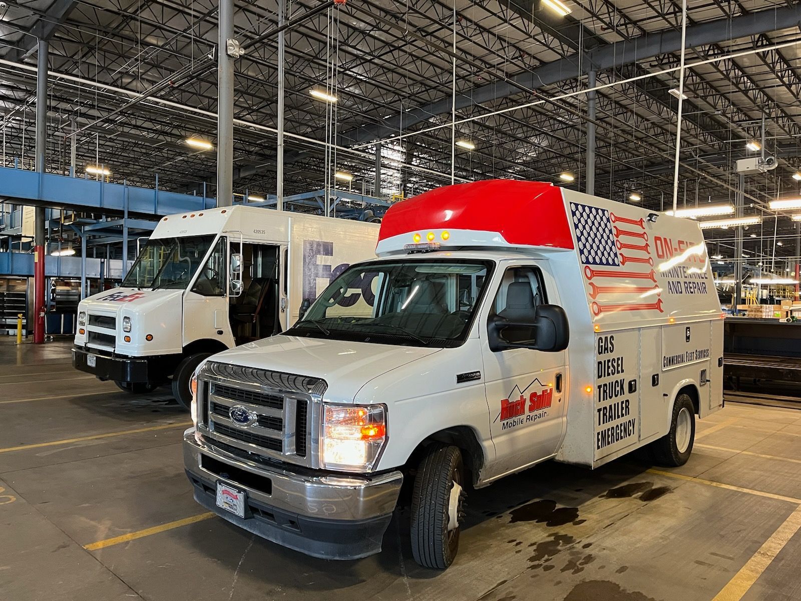 A white van with an American flag on the top is parked in a warehouse.