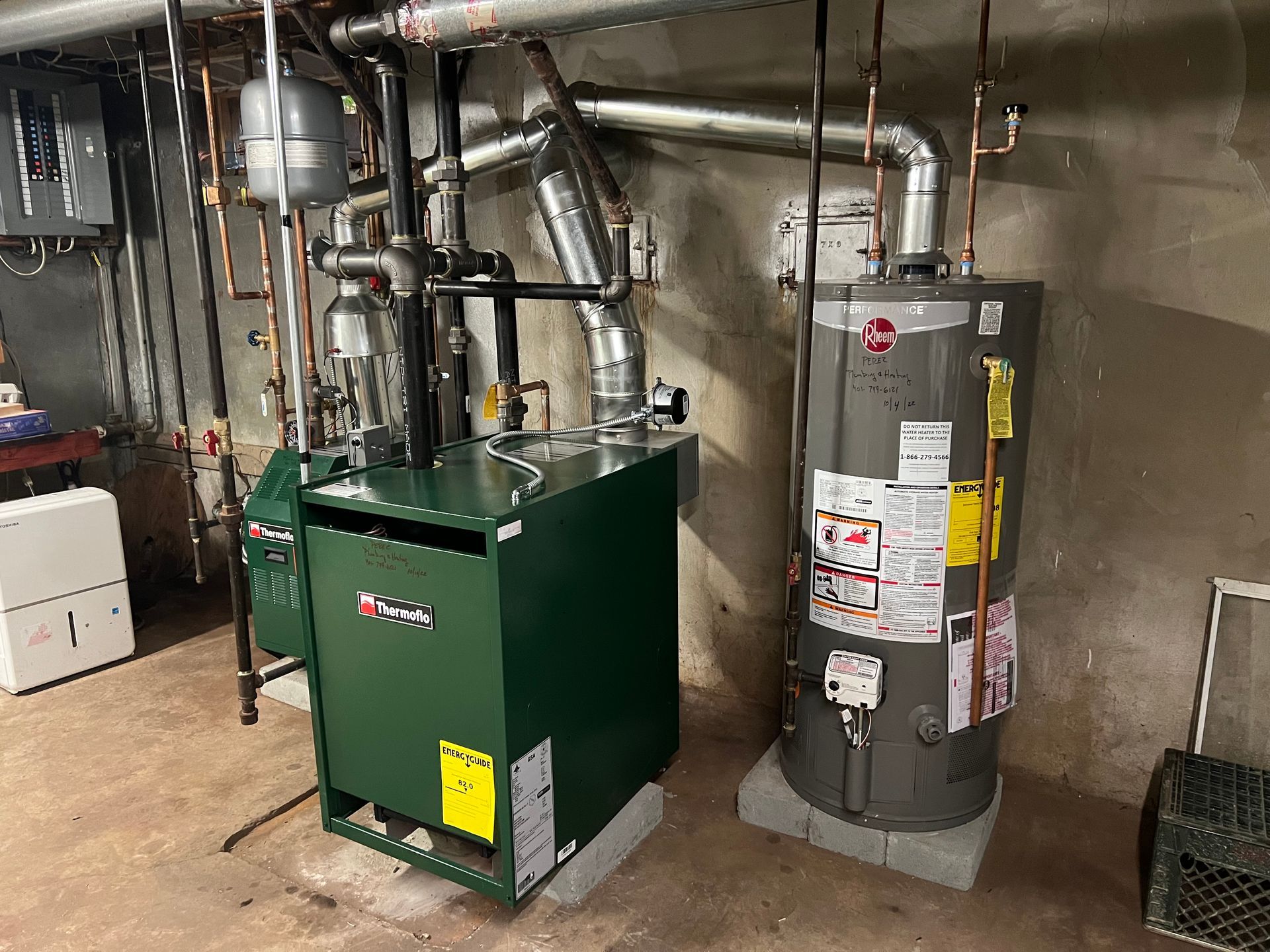 Two water heaters are sitting next to each other in a basement.