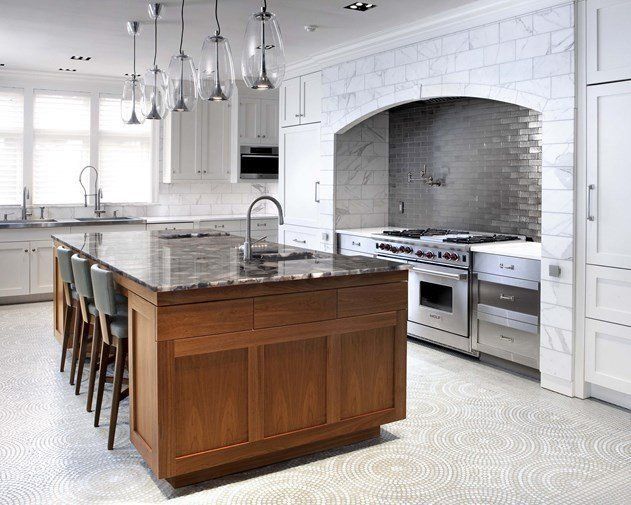 A modern kitchen with a large wooden island, marble countertops, stainless steel appliances, and pendant lighting.