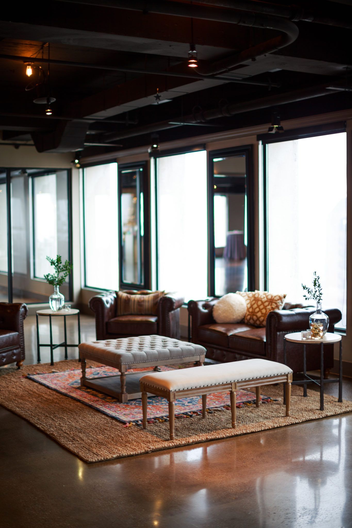Cozy living room with leather armchairs, rug, and windows with sheer shades.
