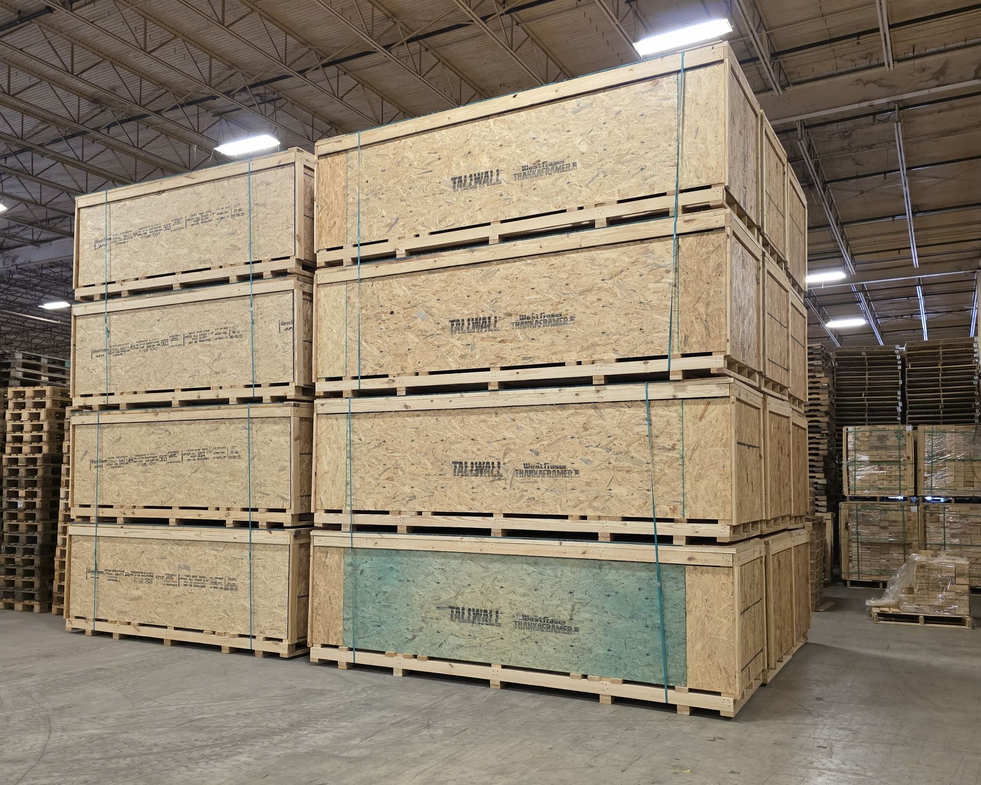 Stacked wooden crates in a warehouse, some marked and banded with straps.