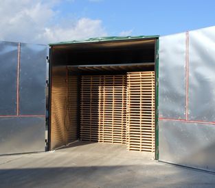 A semi-trailer truck with open doors, loaded with stacks of light-colored wooden shipping pallets.