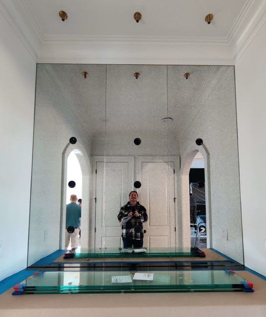 Large mirror installation: workers, arched doorways, doors, and clear glass pieces on the floor.