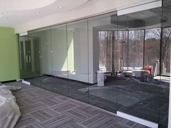 Interior office with glass walls, doors, and a partial view of the outside through a window.