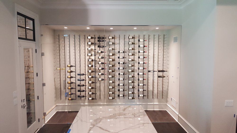 Wine rack built into a wall, with bottles displayed; white trim, dark floors and countertop.