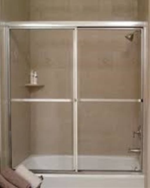 Shower with sliding glass doors, white frame, beige tile walls.