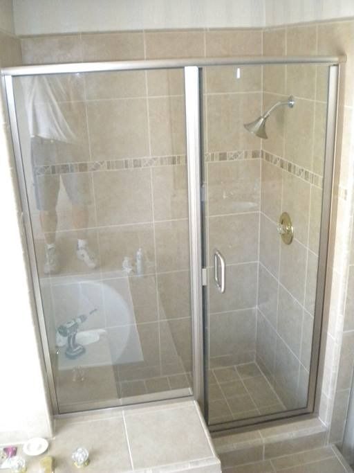 Shower with glass doors and beige tile walls. One door slides open.