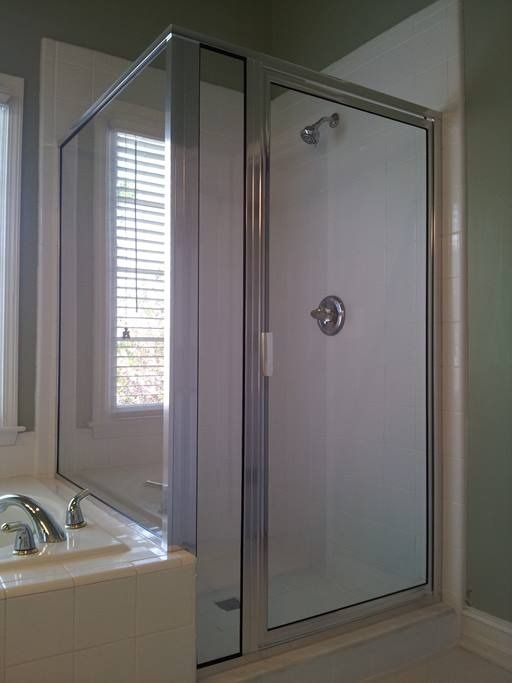 Shower enclosure with glass doors and a chrome frame. Includes a showerhead and water control.