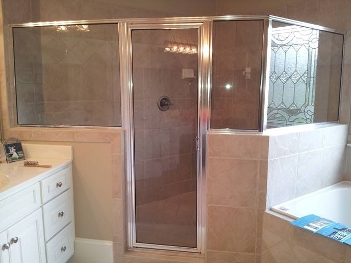 Shower stall with glass doors and tile walls; bathroom setting.
