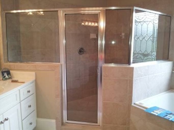 Shower with glass door and side panels, beige tile, and a white vanity.