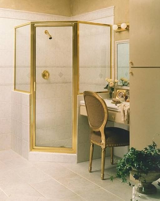 Gold-framed shower stall in a bathroom next to a vanity with a chair.
