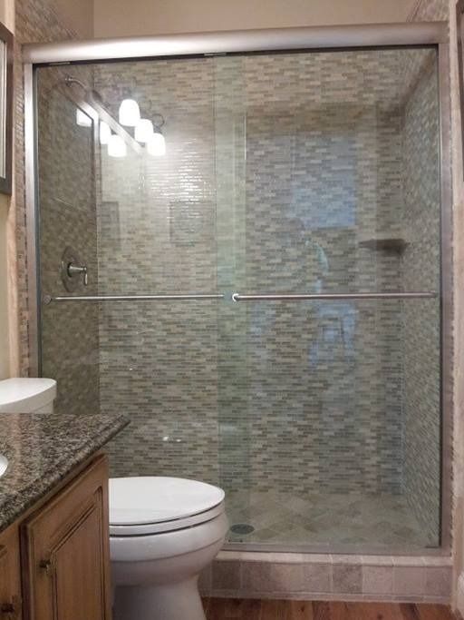 Shower with sliding glass doors and mosaic tile walls in a bathroom.