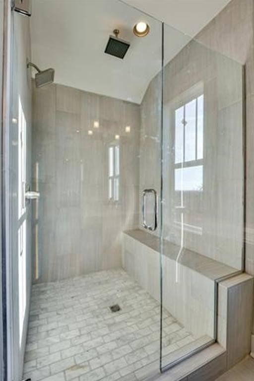 Modern gray-tiled shower with glass enclosure, built-in bench, and window.