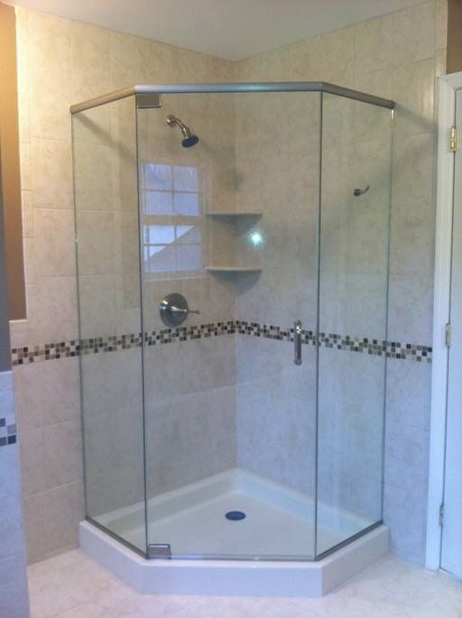A tiled, corner shower with clear glass doors and a chrome showerhead.