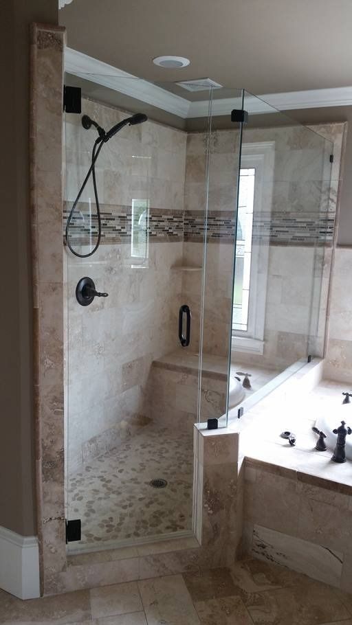 A glass shower enclosure with beige tiled walls and a bench, next to a bathtub.