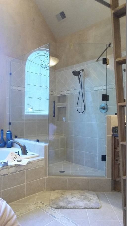 Bathroom with glass shower, soaking tub, light beige tile, and an arched window.