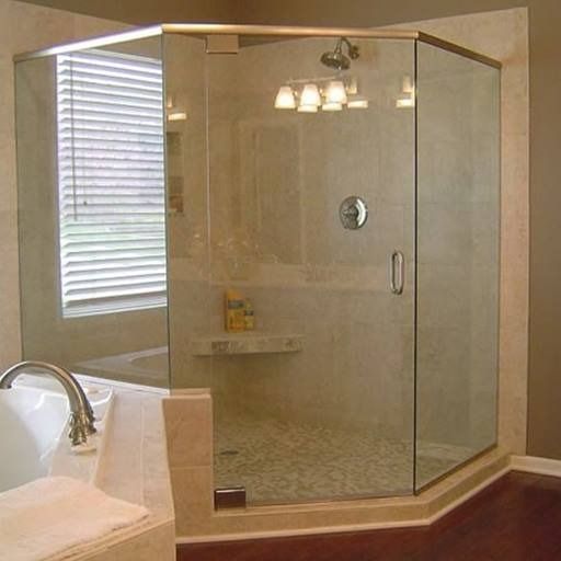 Glass-enclosed shower in a bathroom with a window, tub, and wooden floor.