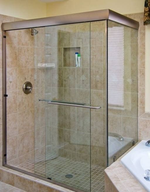 Glass shower enclosure in a bathroom with beige tile walls.
