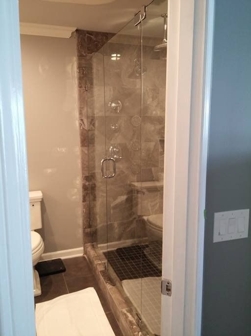 Bathroom with a walk-in shower. Marble walls, glass doors, and a toilet are visible.