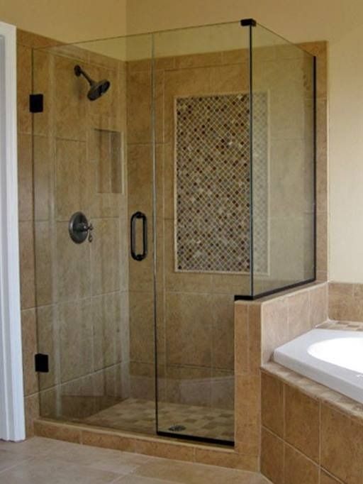 Glass shower enclosure with beige tile walls and decorative tile panel.
