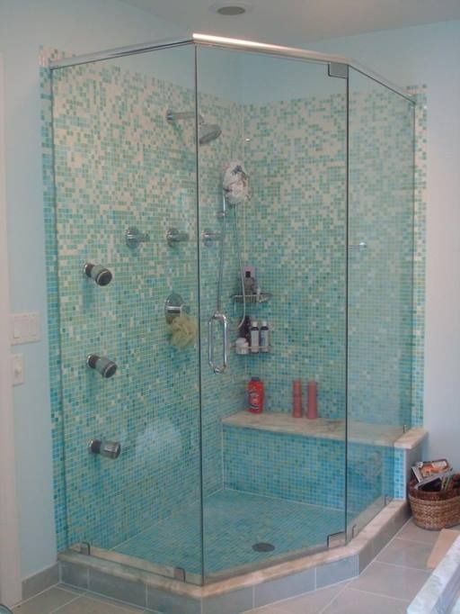 Glass-enclosed shower with turquoise mosaic tile walls, a built-in bench, and multiple showerheads; a basket sits nearby.