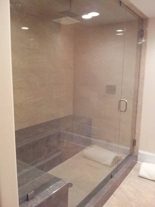 Glass-enclosed shower with stone benches and walls. Features a glass door, and a towel.