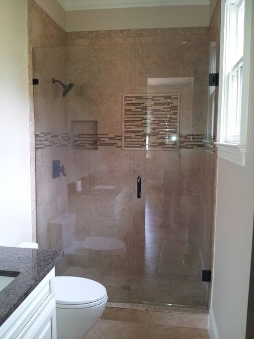 Bathroom with glass shower, neutral-toned tile walls, and a white toilet.