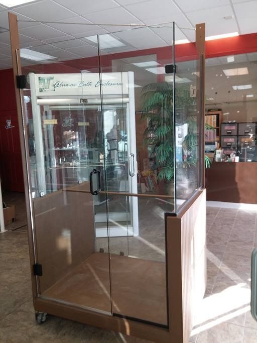 Glass wheelchair lift inside a building, with wood-colored frame.