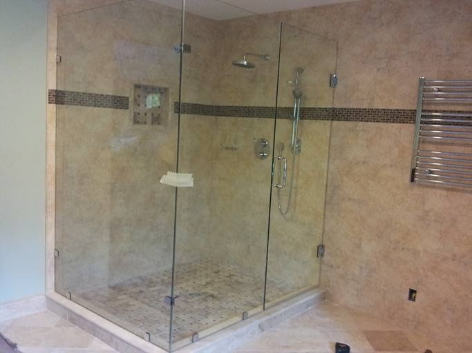Glass-enclosed shower with beige tile walls and mosaic accent stripe. Stainless steel fixtures and heated towel rack.