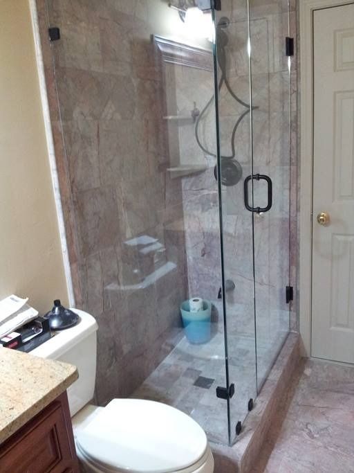 Bathroom with clear glass shower, marble walls, toilet, and vanity.