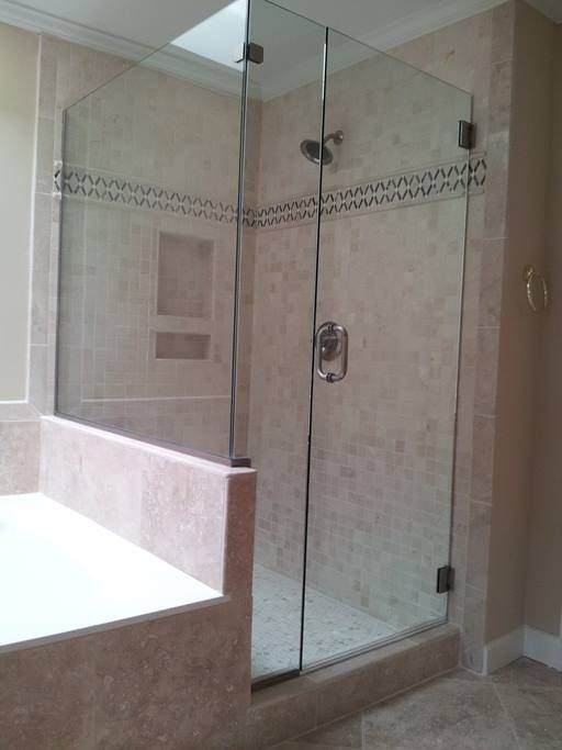 Glass shower enclosure with door, tile walls, and a built-in bench.