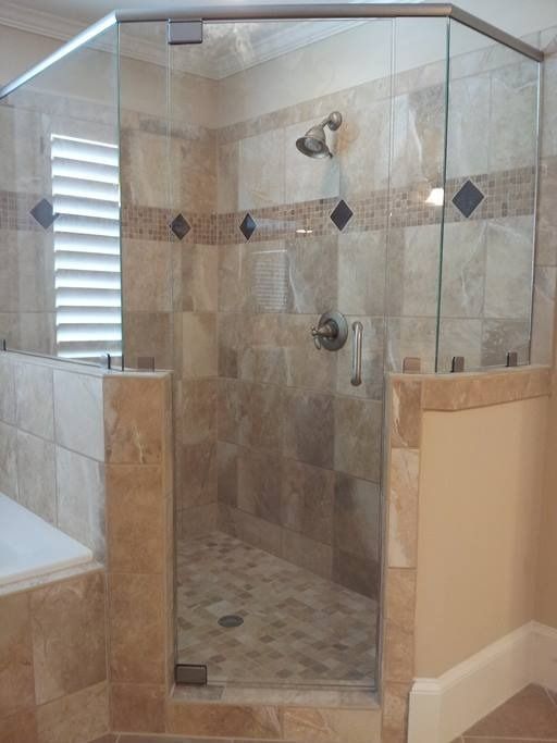 Glass-enclosed shower with beige tile walls and floor; chrome fixtures.