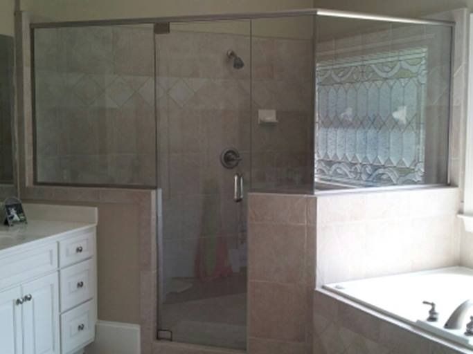 Bathroom with a glass shower enclosure and a white vanity. Beige tile walls. Tub visible on the right.