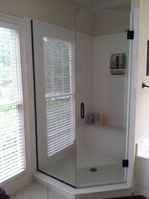 Glass shower enclosure with black trim, corner window, and built-in shelf.