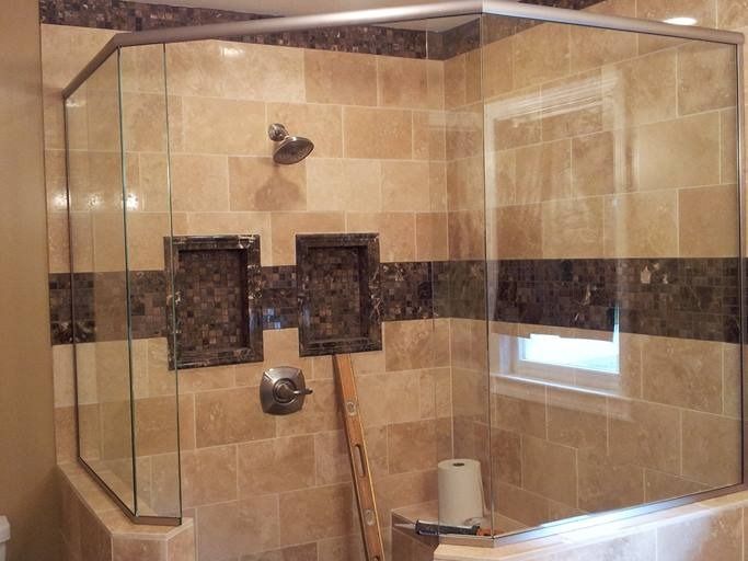 Shower with tan tile walls, granite accents, glass enclosure, and silver fixtures.