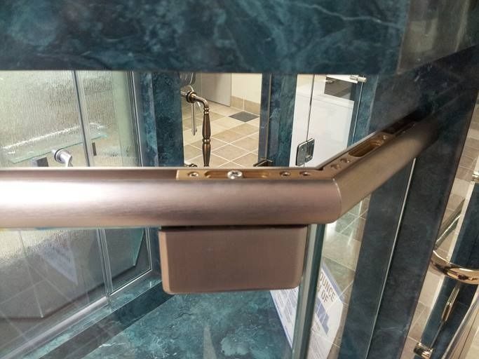 Brown handrail attached to a dark green marble wall in a bathroom.
